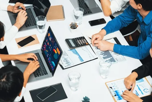 Analyst team utilizing BI Fintech to analyze financial data at table in meeting room. Businesspeople analyzing BI dashboard power on paper for business insight and strategic marketing planning.Prudent